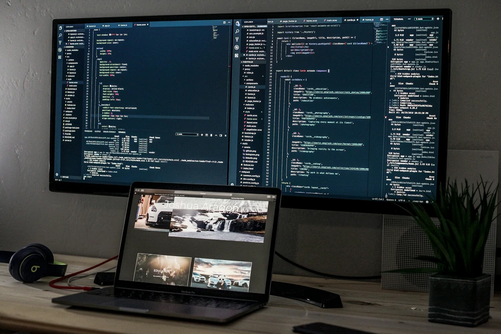 Een ontwikkelwerkplek met een laptop en schermen met code.