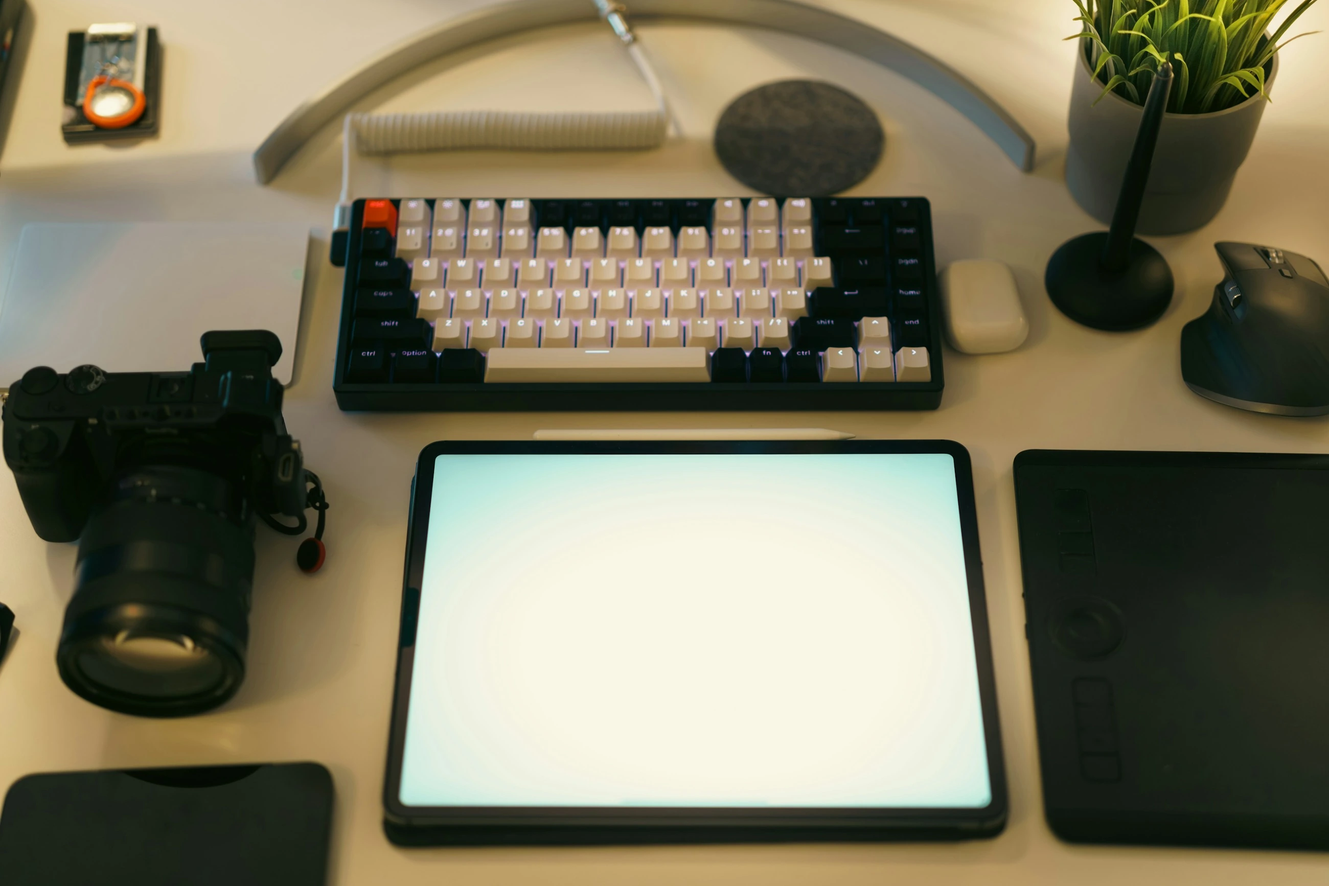 Een creatieve werkplek met computer, tekentablet en camera.