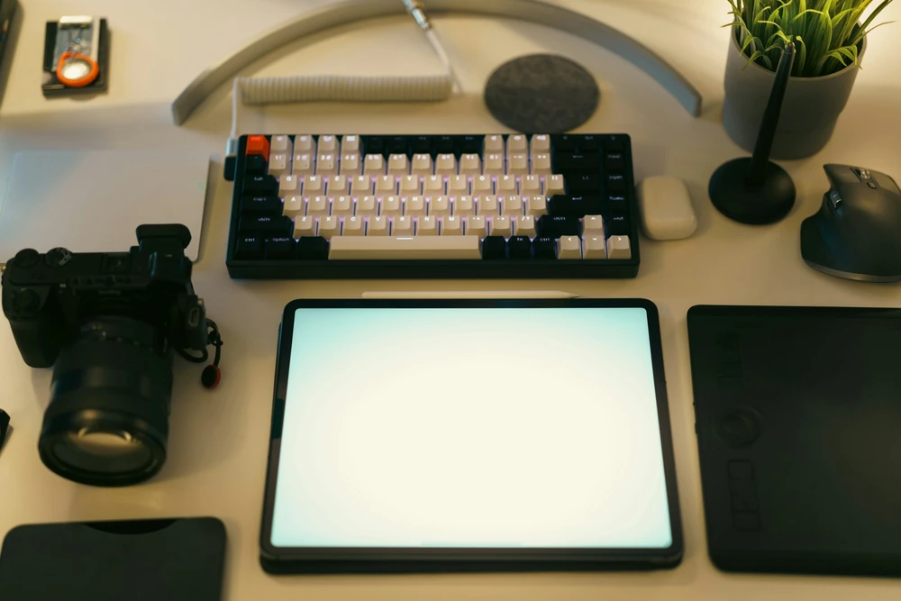 Een creatieve werkplek met computer, tekentablet en camera.