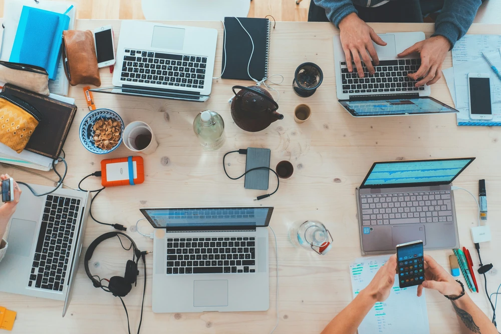 Een team werkt samen aan een tafel met laptops.